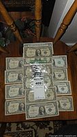 Twelve one-dollar bills on wooden surface including silver certificates and Federal Reserve Notes