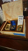 Stone box open on table showing interior and three small containers of jewelry parts