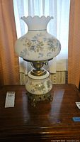 Lamp turned off showing floral painted glass and brass base