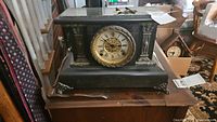 Front view of Seth Thomas Model 295 mantle clock showing black body with gold ornamental clock face and decorative columns on sides