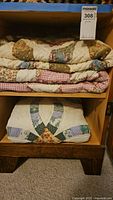 Three folded quilts stacked on wooden shelf