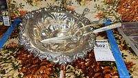 Ornate sterling silver bowl containing serving fork, spoon, and jelly/cake server