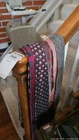 Ties draped over stair railing showing various colors and patterns including solid pink, geometric, and striped