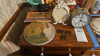 Photo showing all items on a wooden surface including calendar scroll, thermometer plaque, alarm clock, frame stand, and curtain tie back pins.
