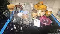 Overview of lot showing various glass jars, ceramic mushroom salt and pepper shakers, ceramic bear honey jar with dipper, and HomeCo mushroom sugar bowl with lid.