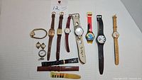 Twelve assorted ladies and men's watches, various brands, including character and vintage styles, with some missing bands and a mix of leather and metal straps.
