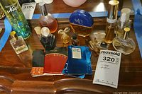 Overview of various perfume and cologne bottles along with sample packets arranged on wooden surface with labels visible on some bottles and packets.