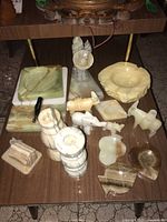 Group photo showing various marble and carved stone decor including candle holders, ashtrays, and small figurines on a wood surface