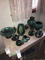 Full view of the Blue Mountain pottery collection on the beige table including bowls, swan vases, pitchers, and decorative pieces.