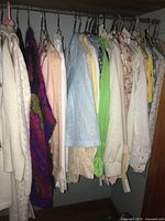 Photo of various women's blouses and sweaters hanging on hangers, assorted colors and materials, all size medium (14)