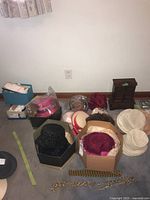 Wide view showing multiple boxes containing ladies hats, gloves, chains and belts, and a wooden jewelry cabinet.