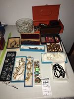 Overview of multiple boxes and a bowl on a table displaying various jewelry pieces including necklaces, watches, earrings and accessories