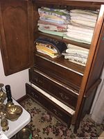 Full view of wooden shelving unit holding stacked linens