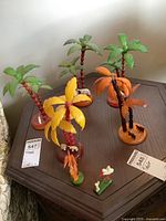 Overview of five plastic palm trees and multiple miniature animal and human figurines on wooden table