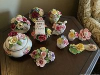 Viewing a group of porcelain floral bouquets and figurines arranged on a table, showing overall lot contents and condition.