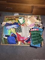 Top view of box filled with assorted scarves and handkerchiefs in multiple colors and patterns.
