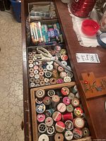 Top-down view of multiple spools of thread, some wooden, some plastic, with a pair of scissors on top.