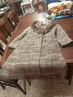 Full view of the wool twill coat laid flat on a table showing the overall shape and fabric pattern.