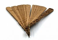 Top view of antique folding sandalwood fan showing carved Chinese characters on fan slats.