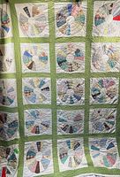 Full view of quilt showing rows of circular patchwork blocks with light green sashing and white background.