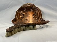 Copper dust pan and matching brush shown on white surface