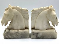 Front view of the two marble horse head bookends side-by-side showing the detailed carving and veining.