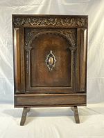 Full frontal image of the hand carved wooden fire screen with floral pattern and arch design.