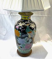 Front view of the lamp with the shade attached, showing colorful floral and bird hand-painted artwork on black enamel-glazed ceramic base sitting on wooden base.