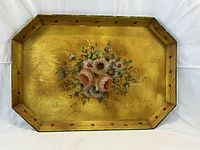 Full view of rectangular gold tole tray with flower motif on flat surface.
