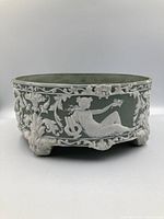 Front angle showing reclining woman holding flower and scrollwork relief