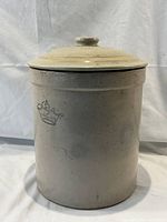 Front view of the vintage stoneware crock with lid showing embossed blue crown mark on the side.