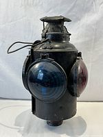 Front angle view of vintage railroad caboose marker lantern showing black metal body and colored lenses on sides.