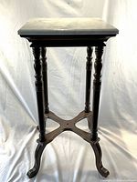 Full view of dark brown wooden plant stand with square white marble top showing turned legs and X-shaped stretcher