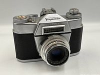 Front angled view showing the Voigtlander Bessamatic camera with attached 50mm f/1.28 Color-Skopar lens, metal body with black leather covering.