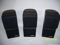 Front view of three pairs (sets) of Bose wall speakers showing black fabric grills with Bose logo and red accent line.