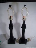 Pair of black modern decor lamps with no shades, brass harp fittings wrapped in plastic.