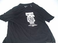 Black short-sleeved T-shirt laid flat showing full front view with Karl Lagerfeld cartoon graphic and logo below.