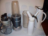 Photo showing NutriBullet blender base, blending container, two clear pitchers, white electric kettle, and white whipped cream dispenser.