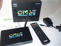 Photo showing the OMG TV streaming media player with antenna, remote control, power adapter, user guide, and original box with MSRP $399 on it.