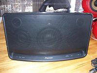 Front side of the black Pioneer wireless powered speaker showing four drivers behind grille and control buttons along bottom edge.