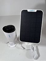 Reolink WiFi solar powered security camera and solar panel side by side showing camera body and panel face