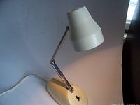 Full view of vintage 12-inch Luxor desk lamp showing white conical shade, adjustable chrome arm, cream plastic base with black toggle switch, and power cord.