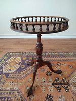 Full view of the round fenced top side table showing turned spindle gallery and original wood finish.
