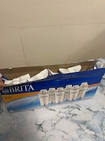 Box of six sealed Brita filter cartridges with blue and white packaging showing six cartridges on front.