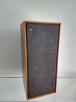 Front view of mid-century modern speaker with teak wood cabinet and dark fabric grill with Celestion logo.