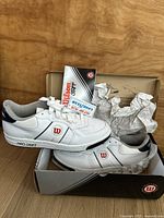 Pair of white Wilson leather tennis shoes with labeling, original box, and tissue paper visible. The shoes show Pro Staff branding and are size 11.