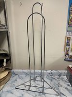 Full front view of the chrome metal hanger stacker rack showing its height and structure with rounded top handles.