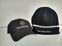 Photo showing the pair of hats: black ball cap with Mercedes-Benz logo and lettering, and black knit beanie with white stripe and 'Mercedes-Benz' text.