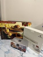 Photo showing three boxed servingware sets: a 3-piece bamboo serving tray set, a 5-piece Bowring white bowls set, and a 4-piece clear glass bowls set