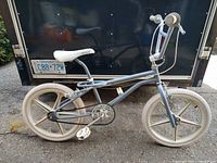 Side profile showing full BMX bicycle with original frame, blue paint, cream Troxel mag wheels, white Dominator seat, and beige grips.
